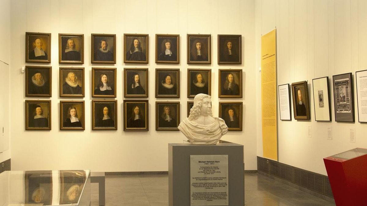 enlarge the image: Blick in die Galerie, an der kurzen Wand 21 Porträts von Professoren des 17. Jhs.in Blockhängung, im Vordergrund eine Vitrine und eine Porträtskulptur