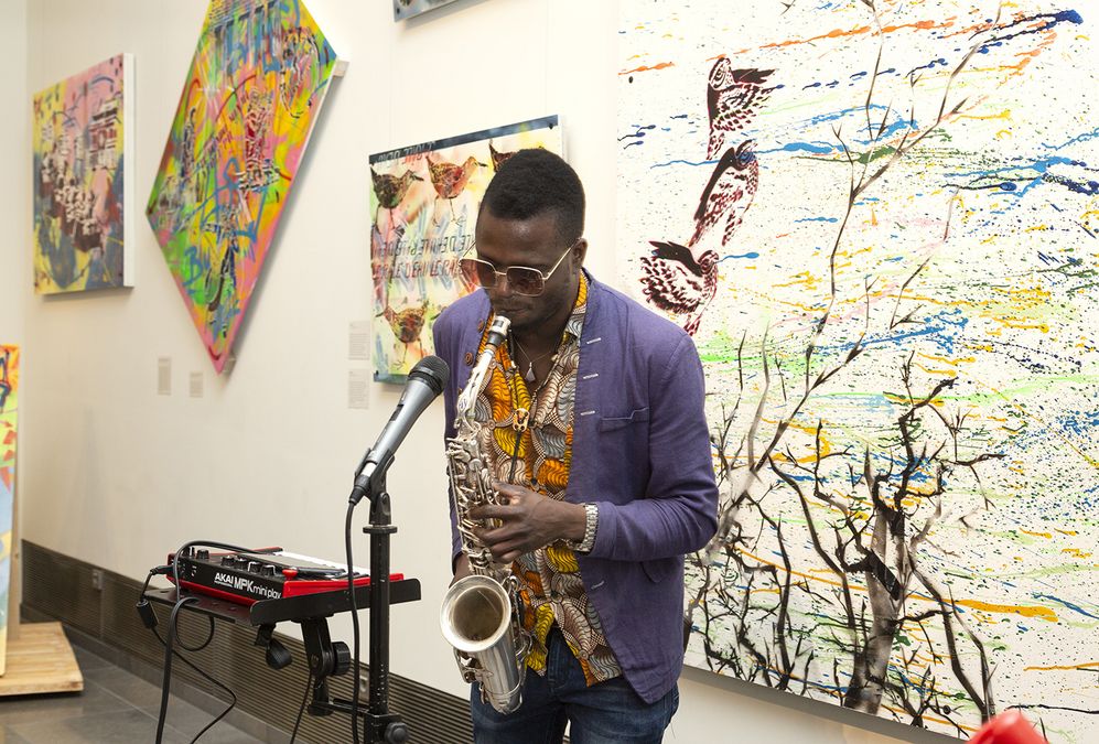 zur Vergrößerungsansicht des Bildes: Saxophonist spielt vor Bildtafeln mit Graffiti