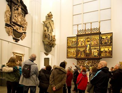 Eine Gruppenführung im Andachtsraum des Paulinums. Die Personen betrachten die Totengedächntnismäler an den Wänden, im Hintergrund steht der Paulineraltar.