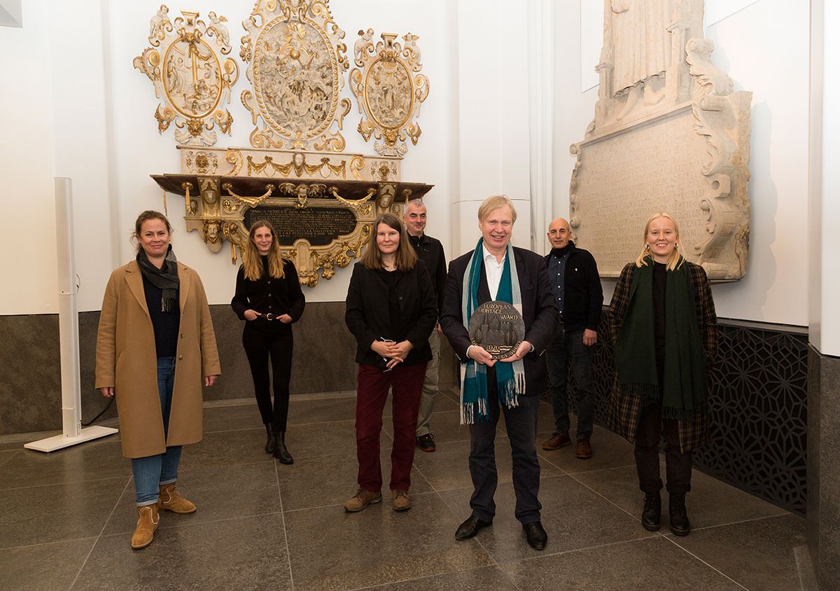 zur Vergrößerungsansicht des Bildes: Das Team der Kustodie steht im Paulinum vor den Epitaphien mit der Europa-Nostra-Palette