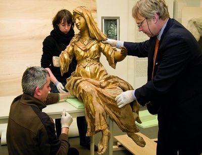 Mitarbeiter und der Kustos der Kustodie betrachten eine goldene, weibliche Figur eines Epitaphen