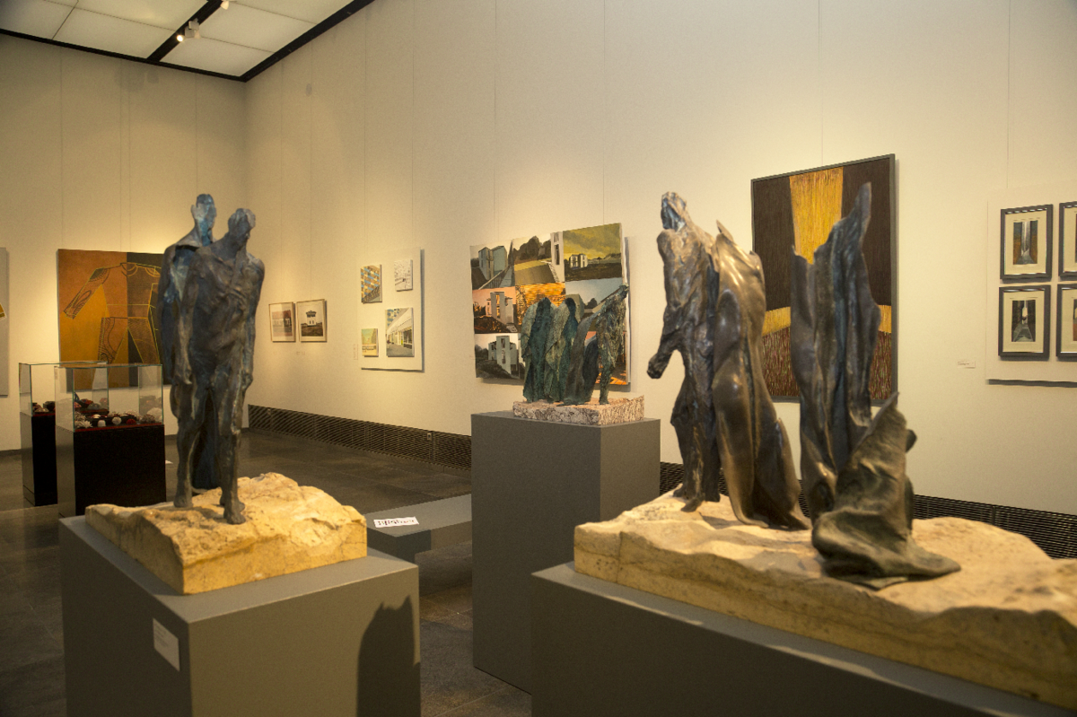 zur Vergrößerungsansicht des Bildes: Blick in den Galerieraum mit Kunstobjekten zeitgenössischer Kunst, an den Wänden Gemälde, im Raum stehen Skulpturen, die abstrakte aber doch menschliche Formen aufweisen