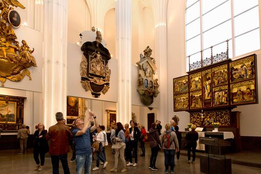 Ansicht des Innenraums des Paulinums Richtung Nordosten, rechts der Altar, an den Wänden und an Hängeflächen Epitaphien, in der Mitte eine Gruppe von Besuchern